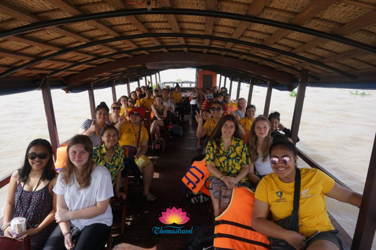 A large teenage group enjoys sitting on a boat at Cai Be on the Mekong River.